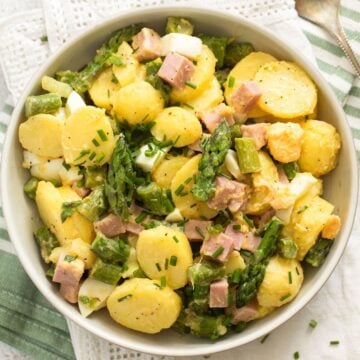 potato and asparagus salad sprinkled with chives in a bowl.