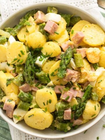 potato and asparagus salad sprinkled with chives in a bowl.