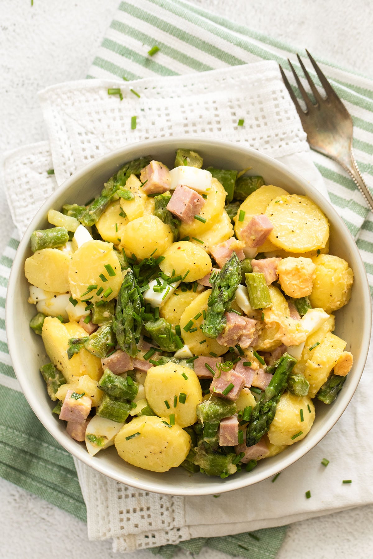 bowl with salad with asparagus, potatoes, ham, eggs, and chives.