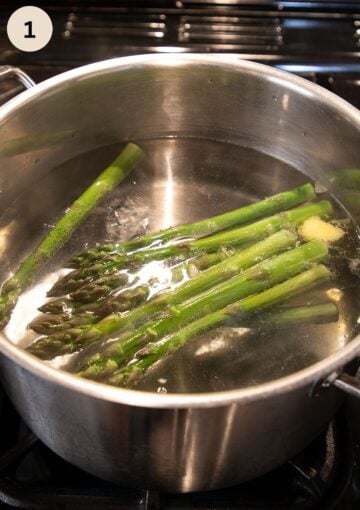 cooking long asparagus spears in a large pot.