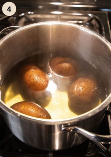 whole potatoes cooking in a large pot for making salad.