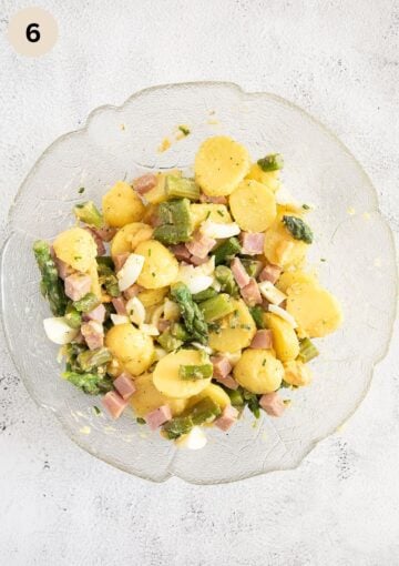 mixed ingredients for making potato, asparagus, egg and ham salad in a large bowl.