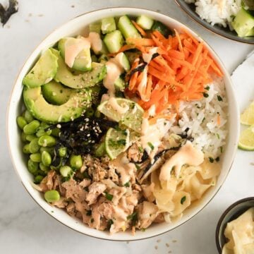 cooked salmon poke bowl with avocado, edamame, carrots, and cucumber.