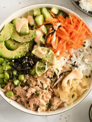 cooked salmon poke bowl with avocado, edamame, carrots, and cucumber.