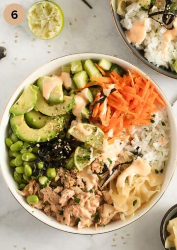 assembled poke bowl with salmon, carrots, avocado, ginger, and rice.