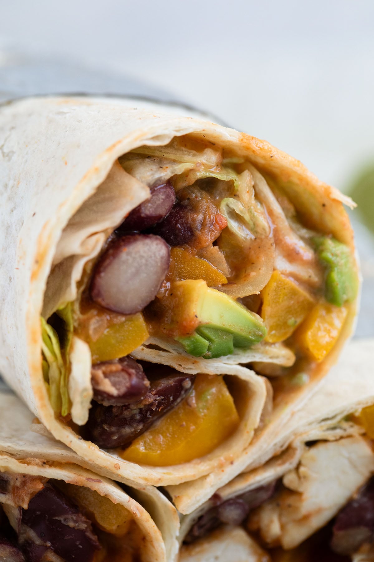 one mexican wrap filled with chicken, beans, vegetables and avocado.