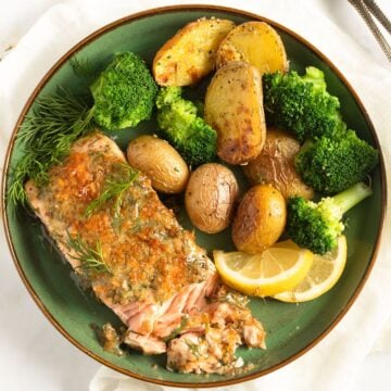 mustard dill salmon, potatoes and broccoli on a green plate.