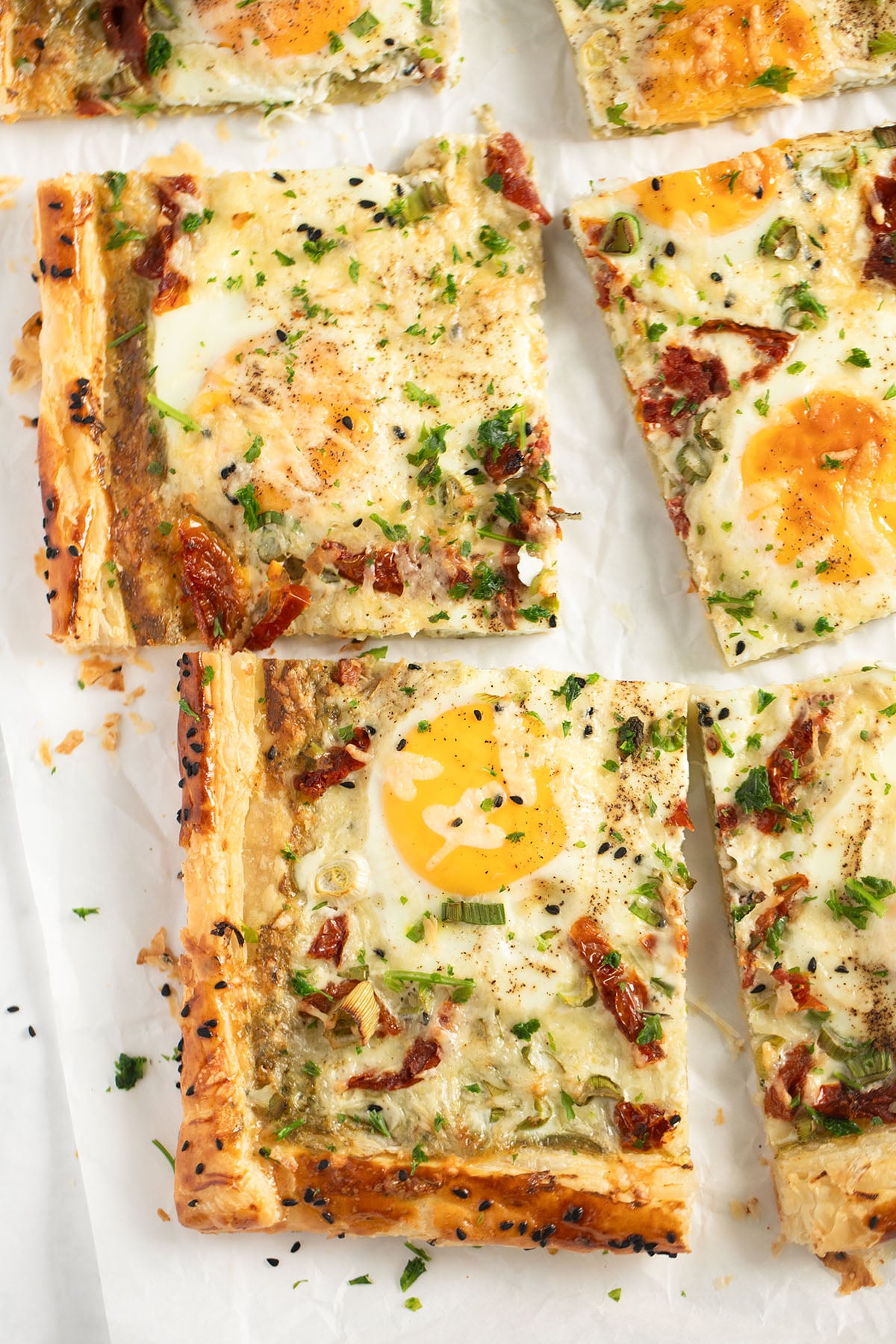 sliced egg puff pastry tarts on white parchment paper.