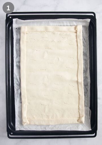 rolled puff pastry on a lined baking sheet with folded edges and pricked with a fork.