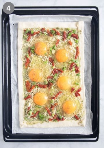 unbaked puff pastry tart with raw eggs cracked on it.