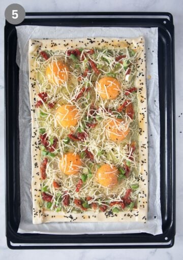unbaked puff pastry tart with eggs, sun-dried tomatoes, green onions, and cheese.