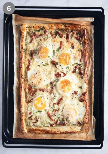 baked puff pastry tart with eggs on a baking sheet.