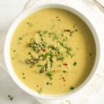 potato and asparagus soup sprinkles with herbs in a large bowl.