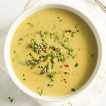 potato and asparagus soup sprinkles with herbs in a large bowl.