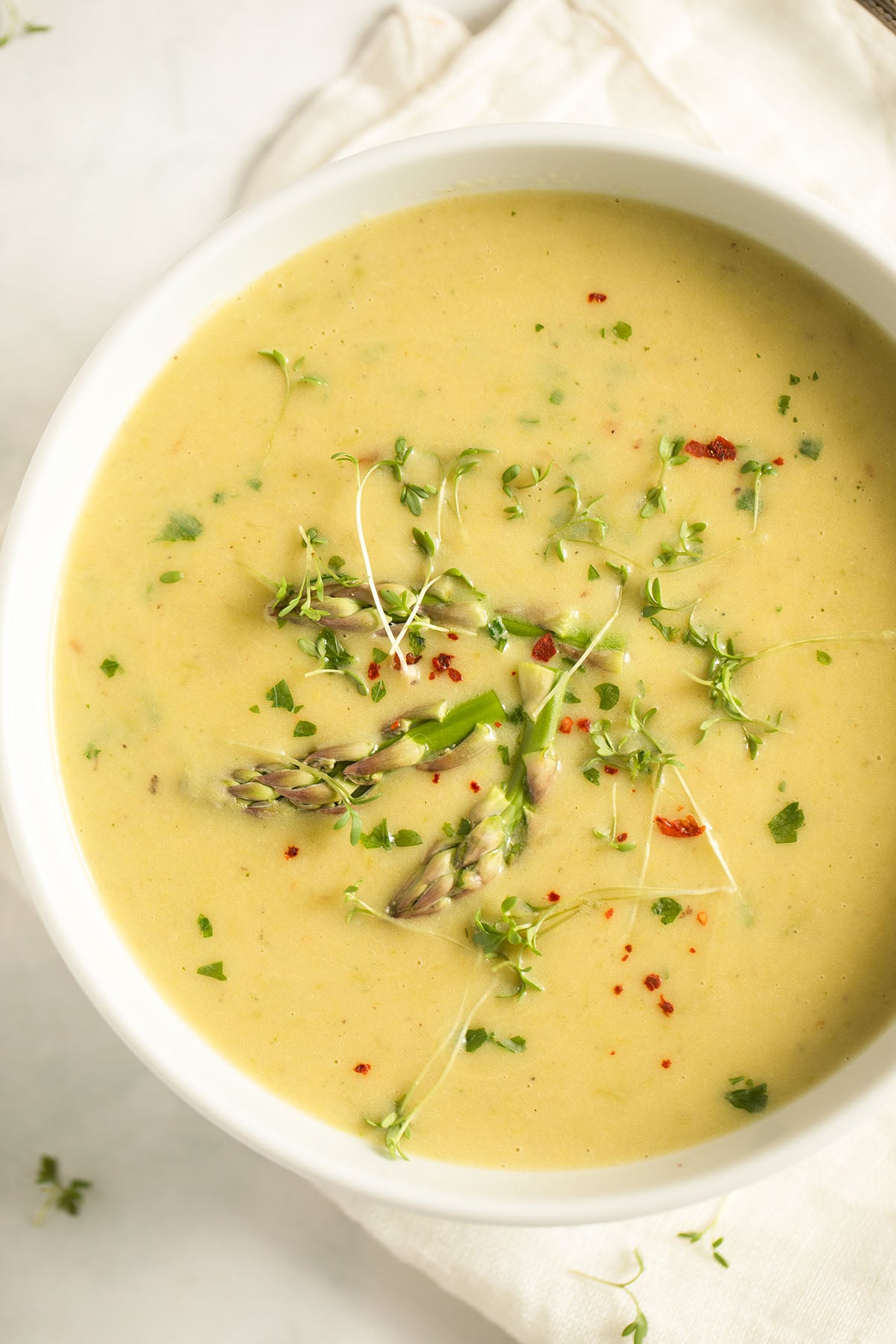 asparagus and potato soup in a bowl on a white kitchen cloth.