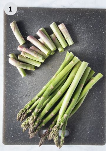 snapped woody ends from asparagus spears on a cutting board.