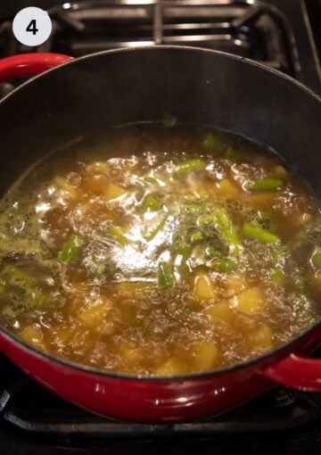 simmering soup with potatoes and asparagus in a dutch oven.