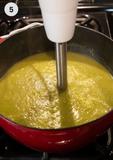blending asparagus potato soup with an immersion blender in a pot.