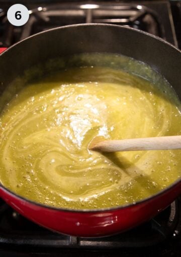stirring heavy cream with a wooden spoon into potato and asparagus soup.