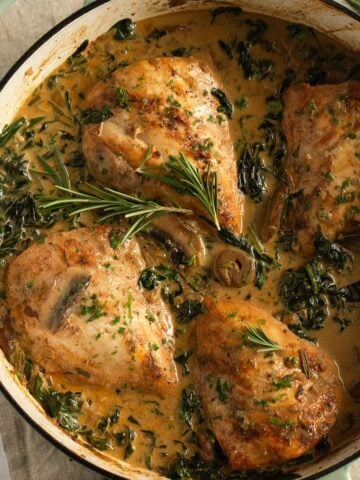 chicken with spinach and mushrooms in a dutch oven.