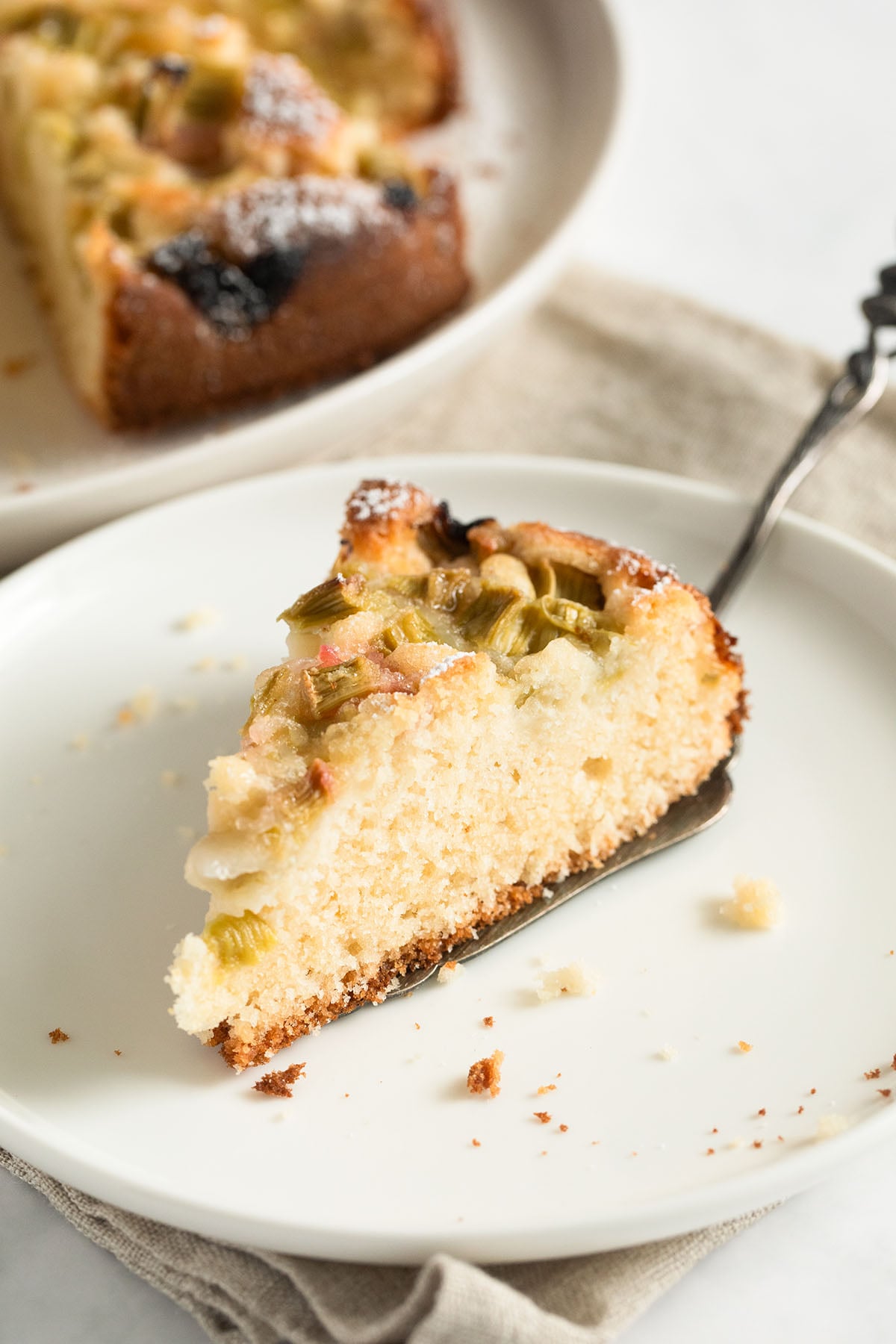 one slice of rhubarb sour cream cake on a cake lifter on a plate.