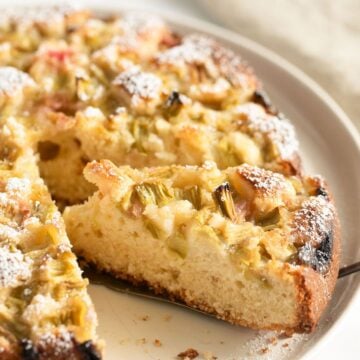 sour cream rhubarb cake sliced on a cake plate.