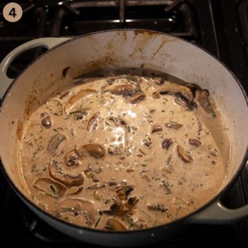 mushrooms cooking in cream sauce in a dutch oven.