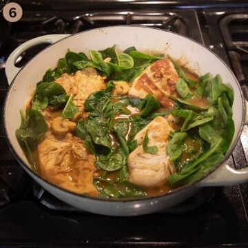 adding baby spinach to chicken breasts in cream sauce.