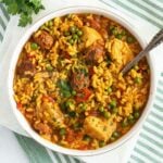 chicken chorizo paella in a large bowl with a spoon sticking into it.