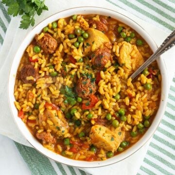 chicken chorizo paella in a large bowl with a spoon sticking into it.