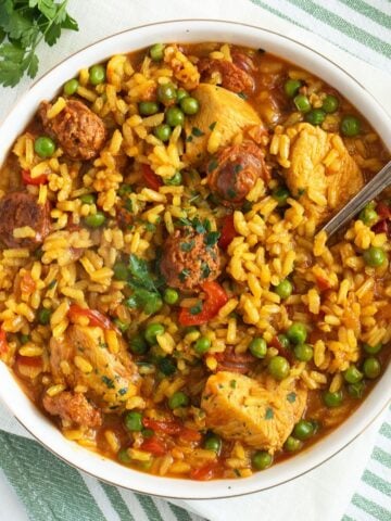 chicken chorizo paella in a large bowl with a spoon sticking into it.