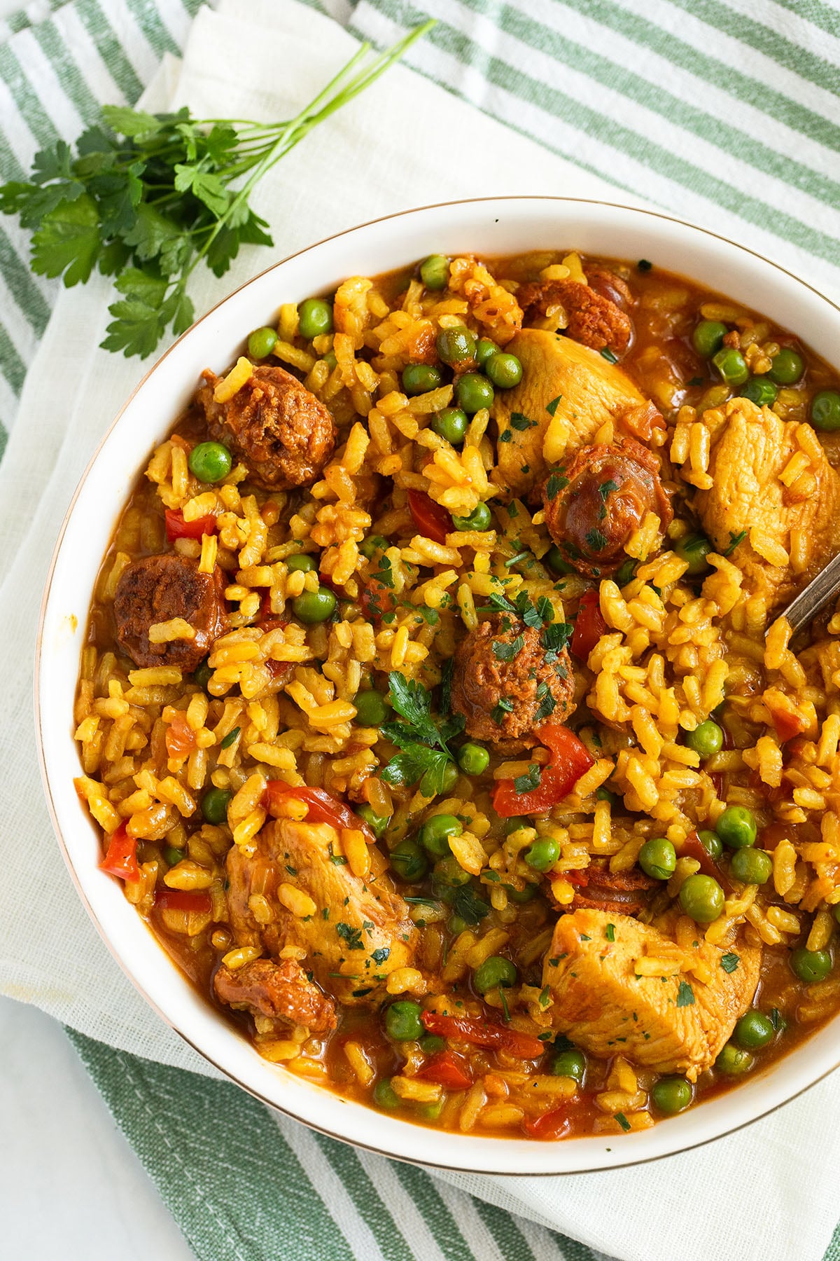 chicken and chorizo paella in a bowll and a sprig of parsley near it.