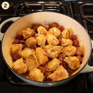 cooking chicken breast pieces and chorizo slices in a pot to make paella.