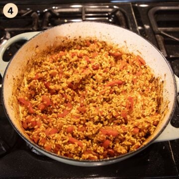 stirring rice with vegetable in a pot to make paella.