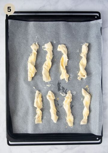 unbaked puff pastry and cream cheese twists on a lined baking sheet.