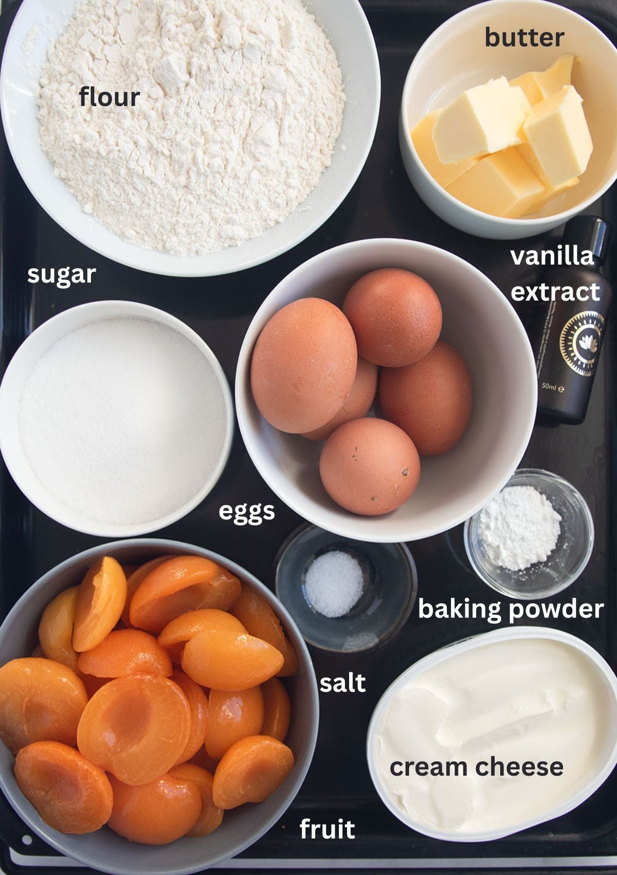listed ingredients for making crumble cake with flour, eggs, butter, sugar, cream cheese and apricots.