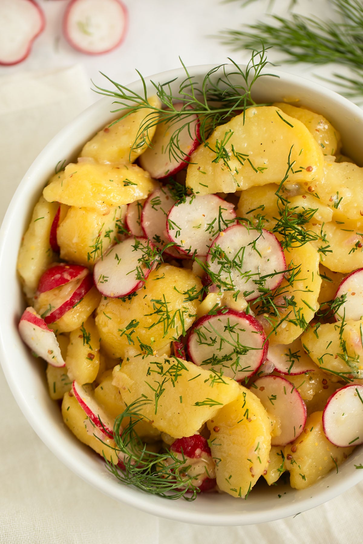 radish and potato salad with dill and mustard dressing in a large bowl.