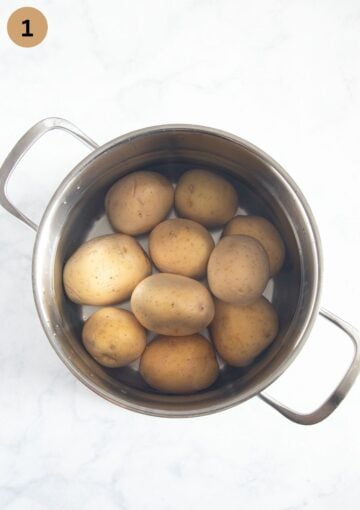whole, unpeeled potatoes boiling in a pot of water.