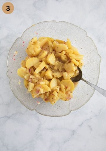 tossing cooked and sliced potatoes with warm dressing to make salad.