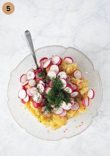 adding sliced radishes and chopped dill to sliced potatoes to make salad.