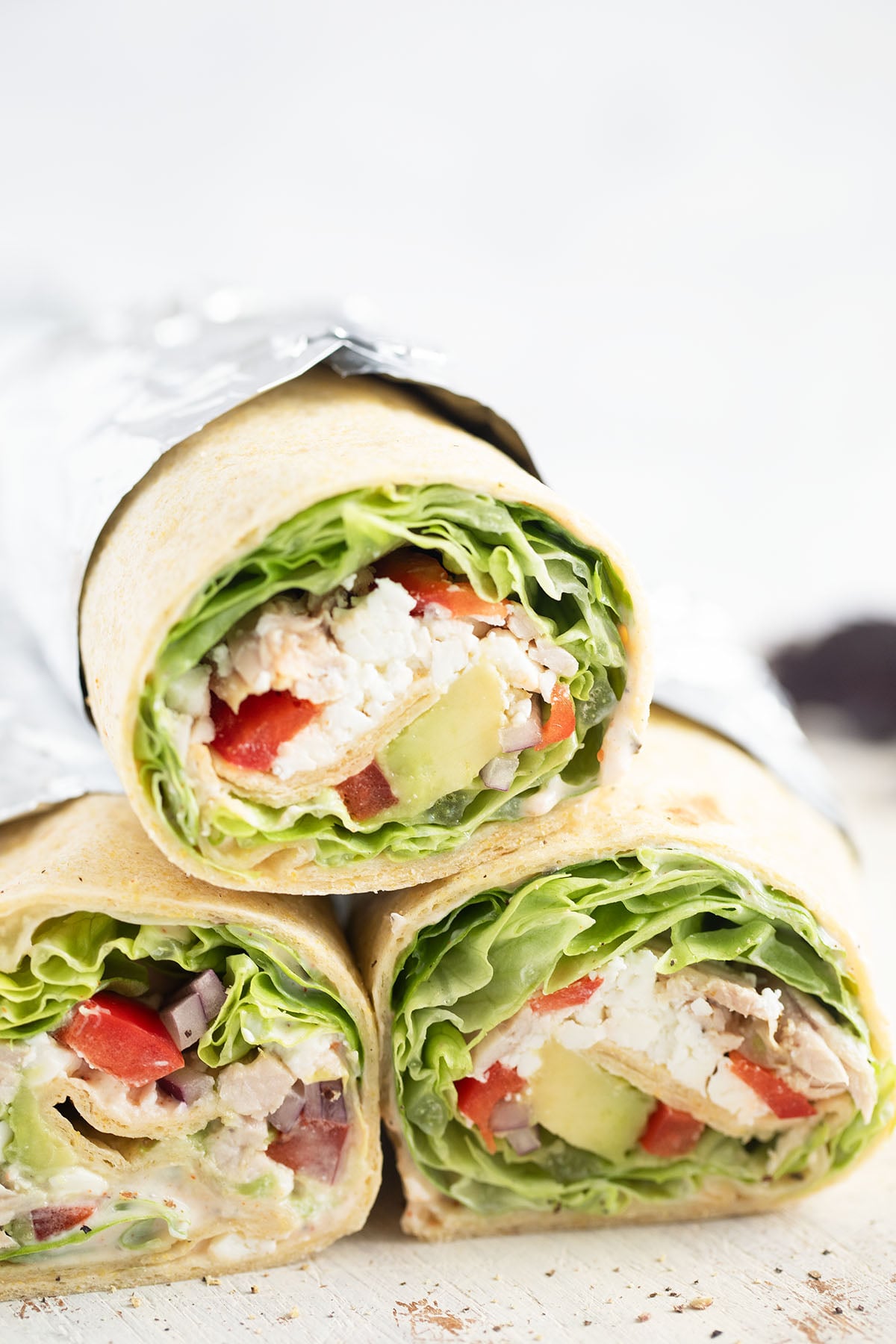 three wraps with shredded chicken and veggies cut to show the filling.