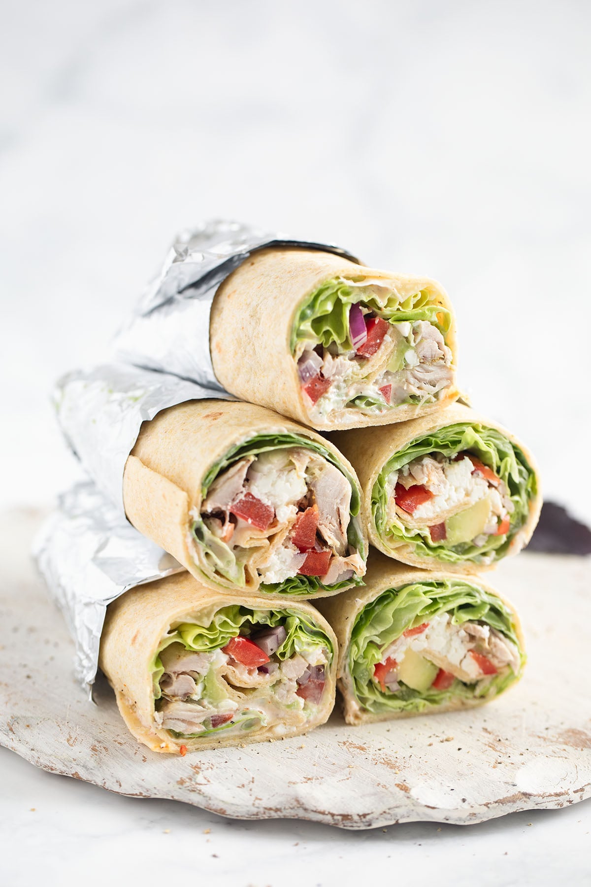 many stapled shredded chicken wraps cut to show the filling.
