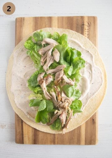 adding shredded chicken and lettuce to tortilla wraps.