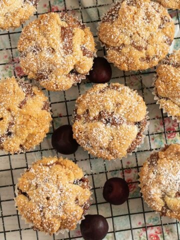 cherry streusel muffins sprinkled with confectioners's sugar and a few fresh cherries.