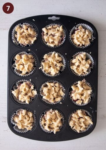 unbaked cherry muffins topped with streusel in a muffin pan.