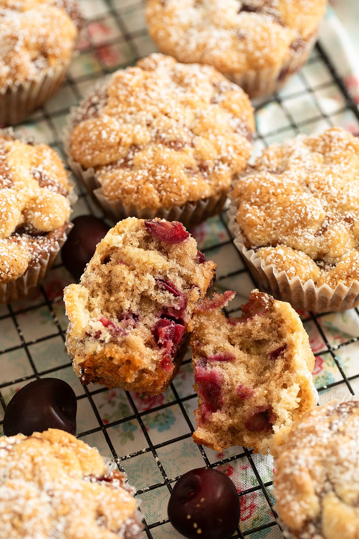 many cherry muffins, one split in the middle showing the crumb and the cherries.