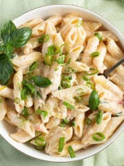 green onion pasta or scallion pasta garnished with basil in a bowl.