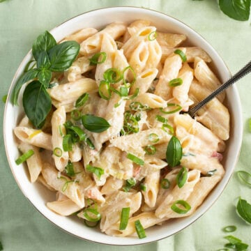 green onion pasta or scallion pasta garnished with basil in a bowl.