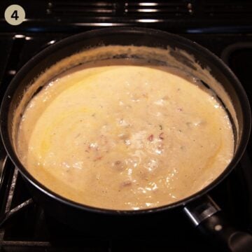 simmering green onion and cream cheese sauce for pasta in a saucepan.