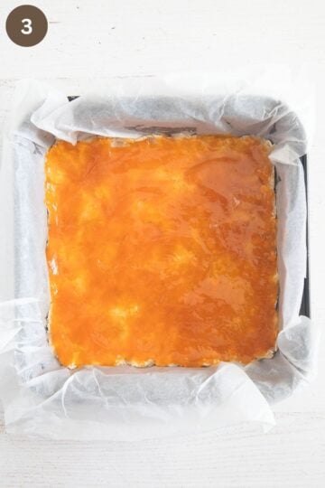 base for crumble bars spread with peach jam.